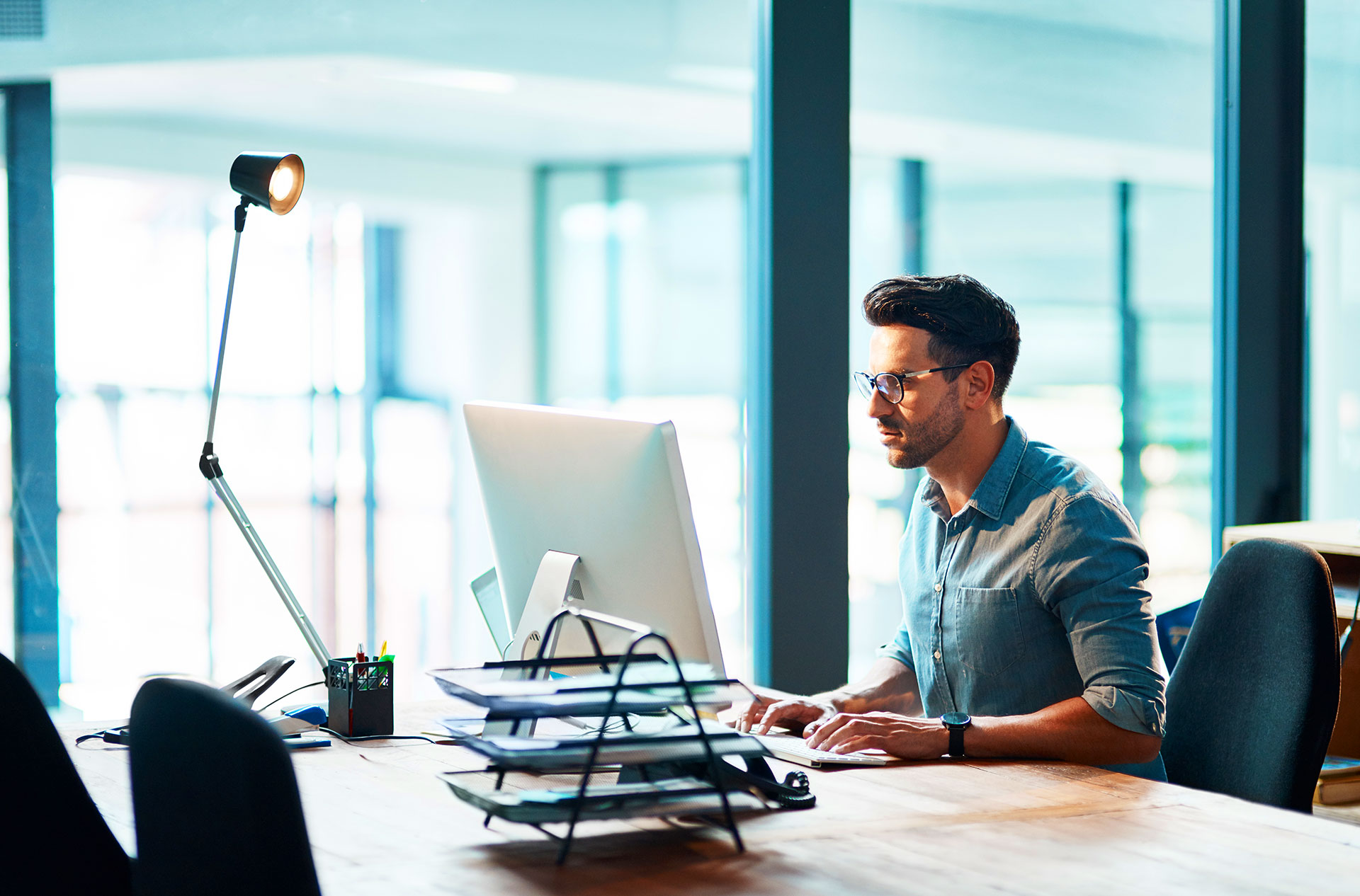 Male professional working focused at desktop computer in bright modern office