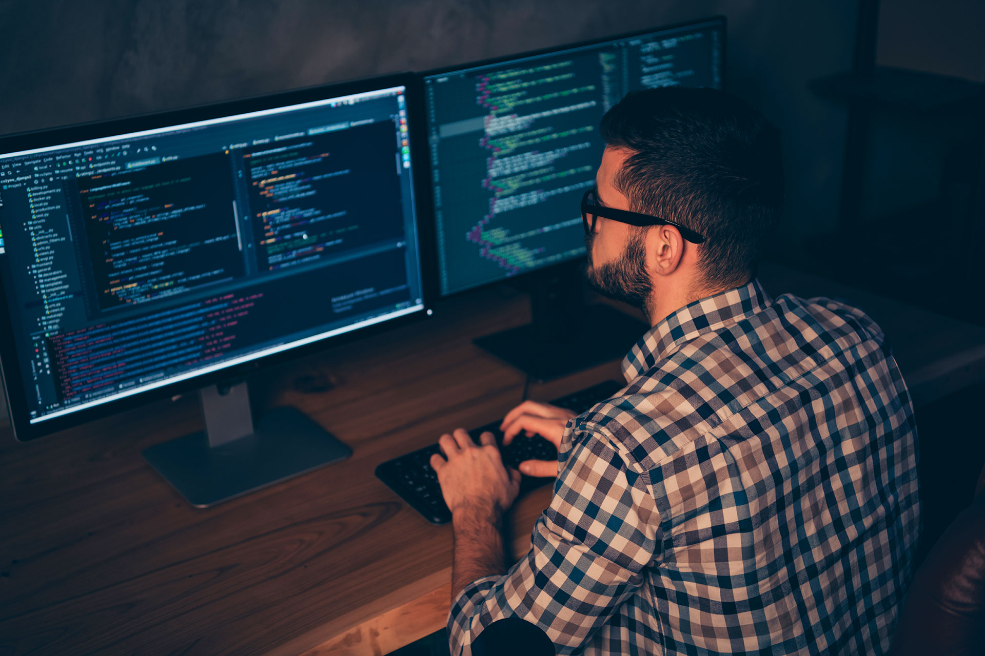 Developer coding on dual monitors with programming software