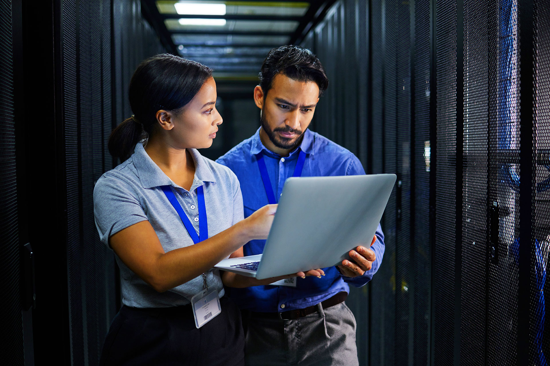 IT specialists reviewing laptop data inside server room
