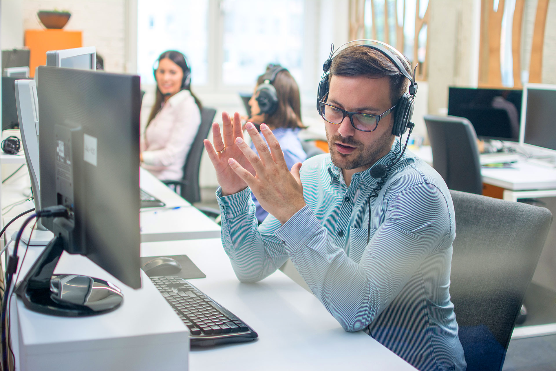 Call center agent gesturing while assisting customer on headset