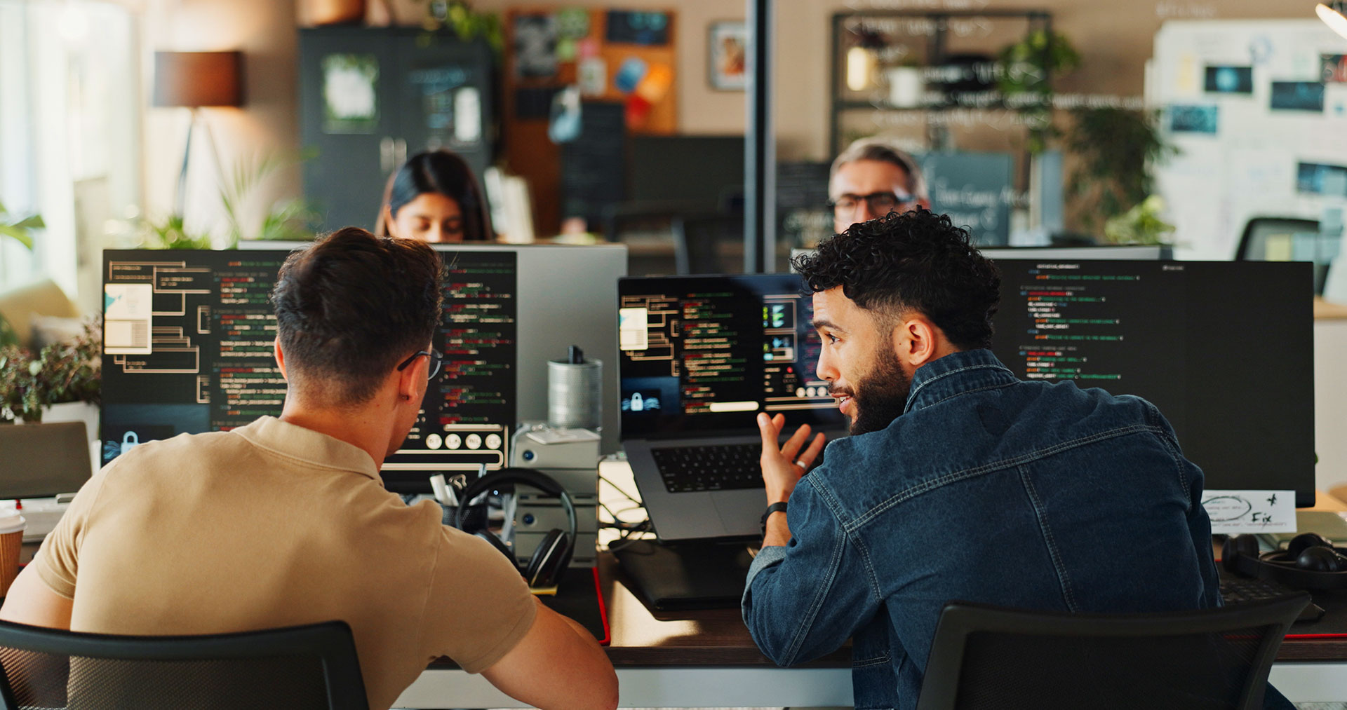 Two IT professionals discussing code on dual monitor setup